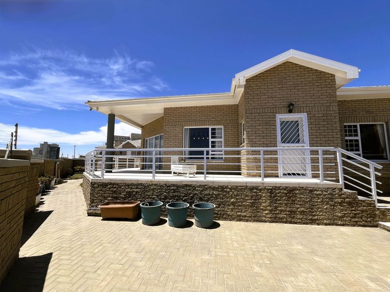 A well-maintained rear exterior view of the townhouse featuring a paved patio, covered veranda, and brick facade with secure access points.