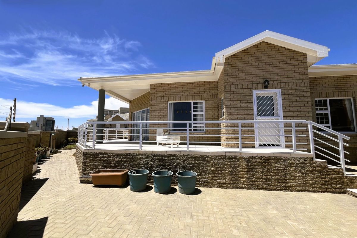 A well-maintained rear exterior view of the townhouse featuring a paved patio, covered veranda, and brick facade with secure access points.