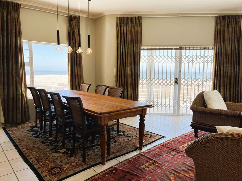 Spacious dining area featuring ceramic tile flooring, modern pendant lighting, and large sliding glass doors offering direct access to the patio and ocean views.