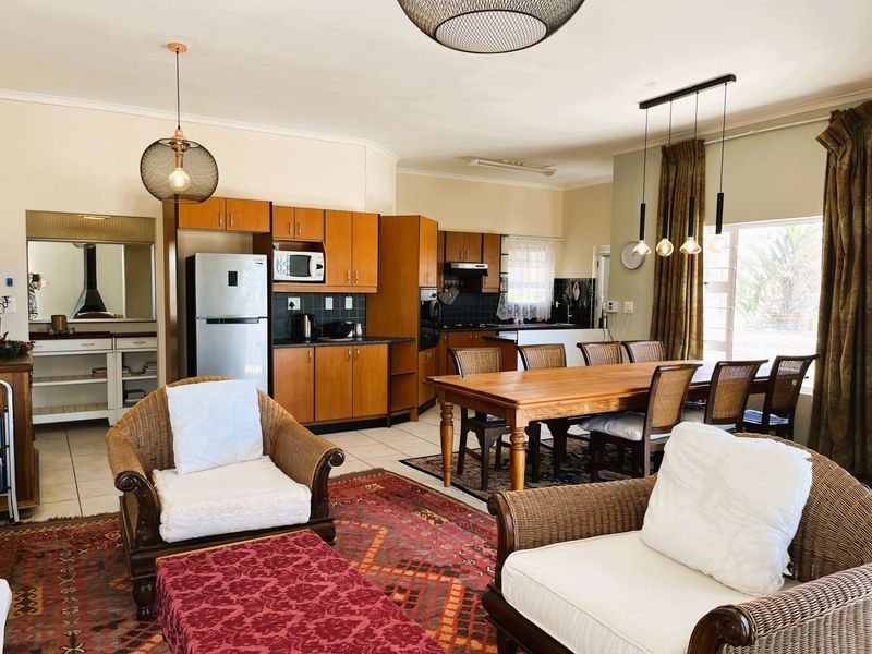 Open-plan living and dining area featuring a functional kitchen with wood-finish cabinetry, tiled floors, and integrated lighting fixtures.