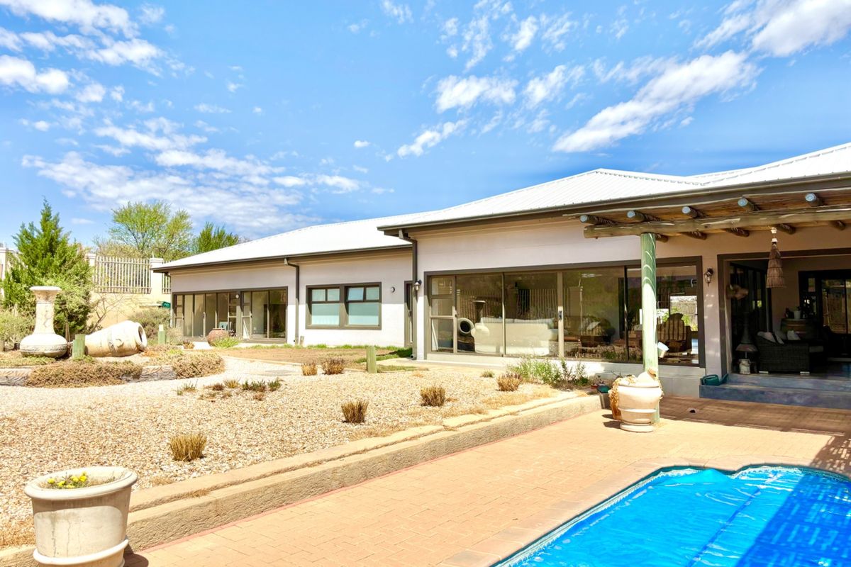 Rear view of the property featuring a swimming pool, paved patio area, and a covered pergola attached to the main house structure.
