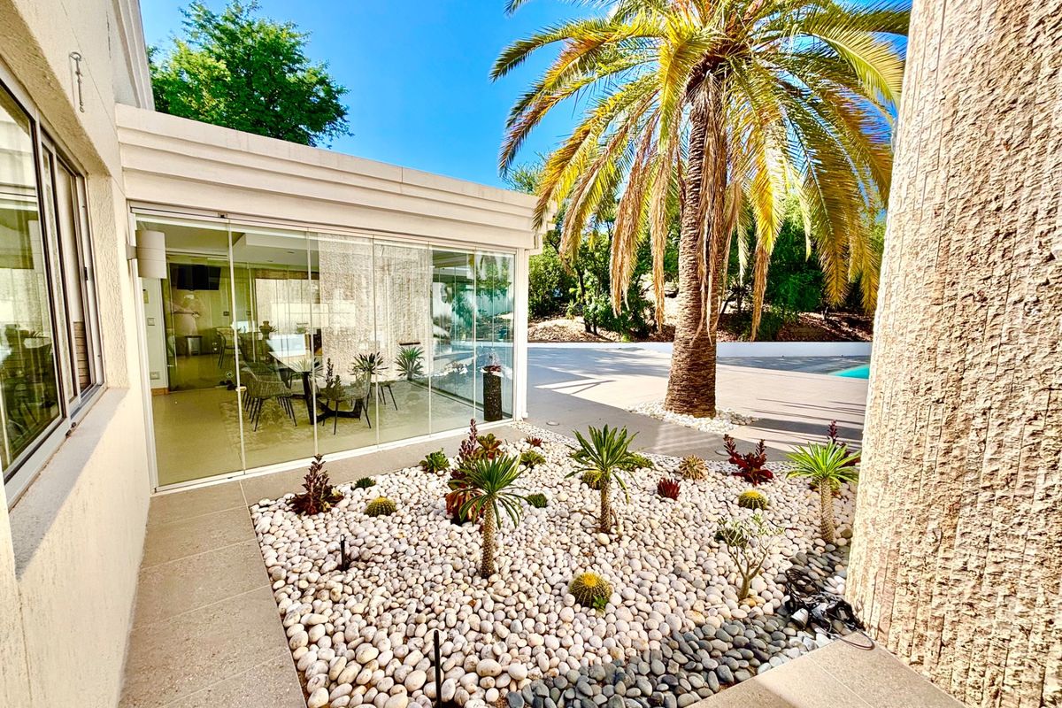 A view of a landscaped garden area with decorative stone beds and a glass-enclosed patio space adjacent to the main dwelling.