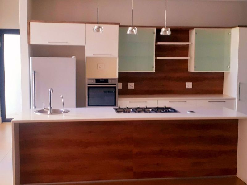 Modern kitchen featuring a central island with a gas hob and sink, complemented by sleek built-in cabinetry and integrated oven.