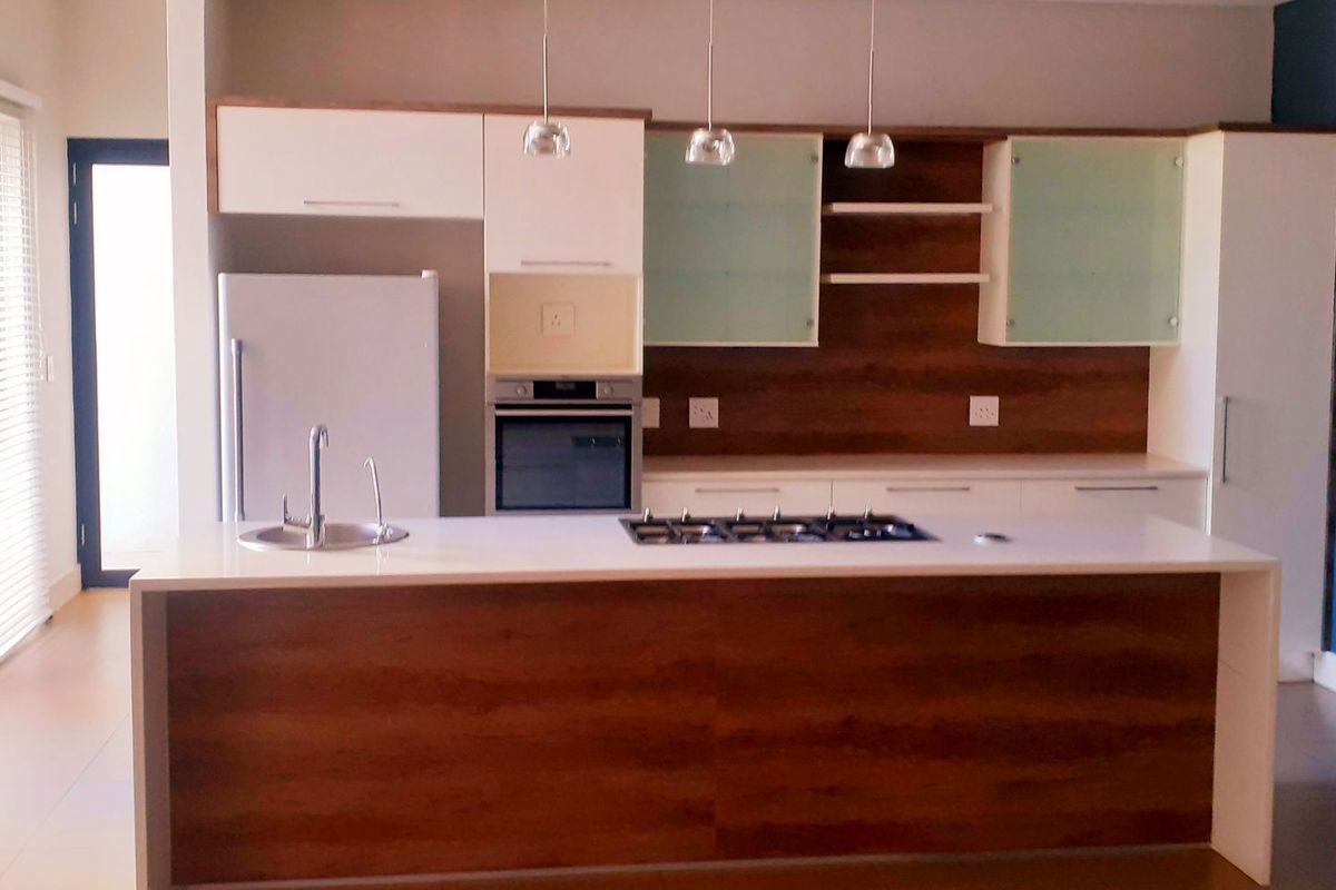 Modern kitchen featuring a central island with a gas hob and sink, complemented by sleek built-in cabinetry and integrated oven.