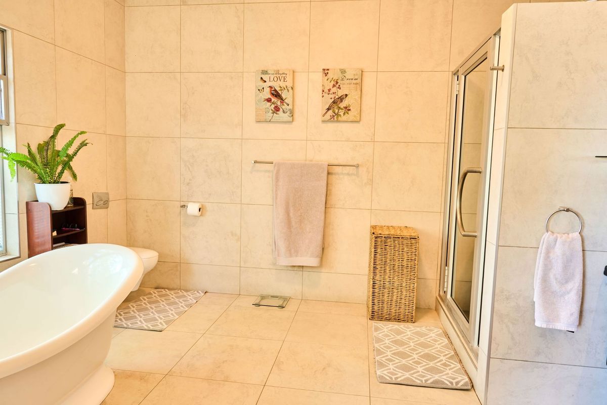 A well-maintained bathroom featuring a modern freestanding bathtub, a glass-enclosed shower, and neutral ceramic tiling throughout.