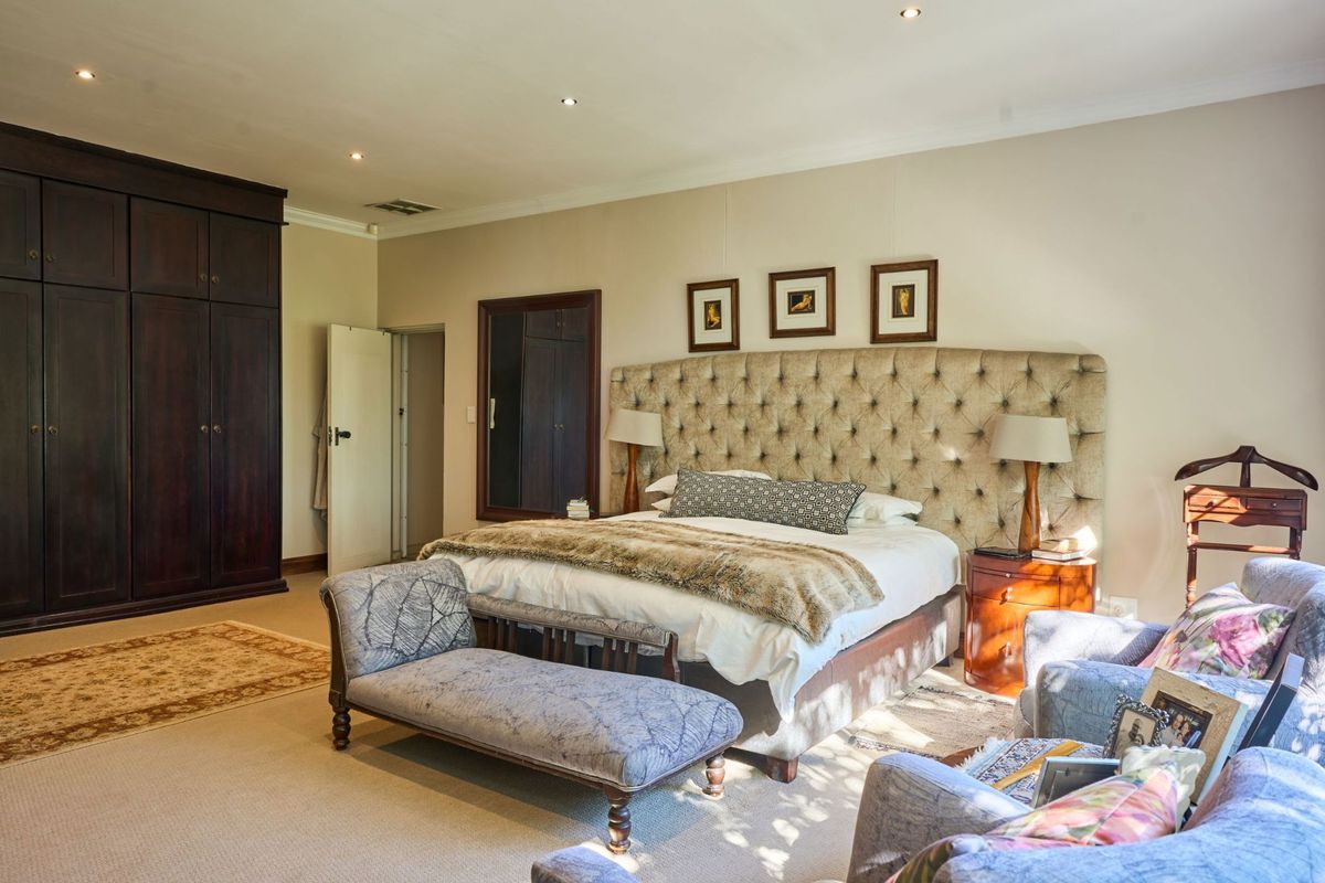 Spacious bedroom featuring neutral walls, carpeted flooring, recessed downlighting, and extensive dark wood built-in cabinetry.