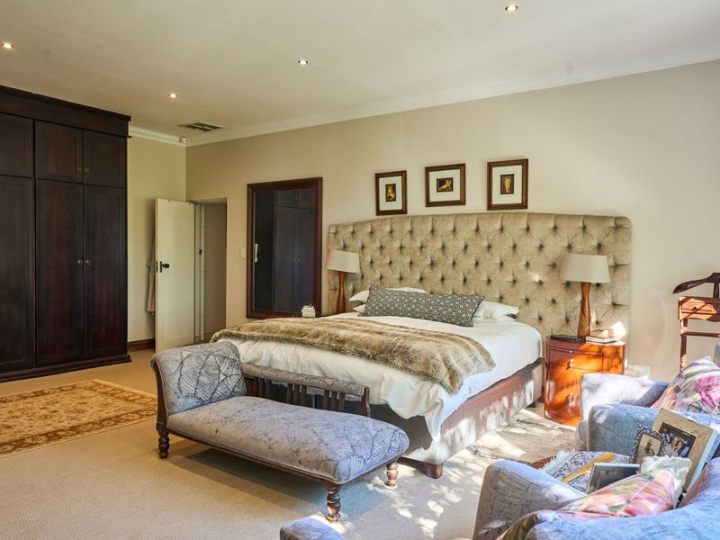 Spacious bedroom featuring neutral walls, carpeted flooring, recessed downlighting, and extensive dark wood built-in cabinetry.
