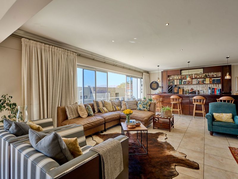 Spacious open-plan living area featuring a built-in bar, large sliding glass doors for natural light, and neutral tiled flooring.
