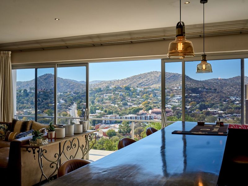 Spacious open-plan living area featuring a built-in bar counter and expansive sliding glass doors that showcase panoramic mountain and city views.