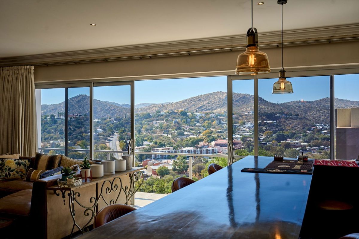 Spacious open-plan living area featuring a built-in bar counter and expansive sliding glass doors that showcase panoramic mountain and city views.