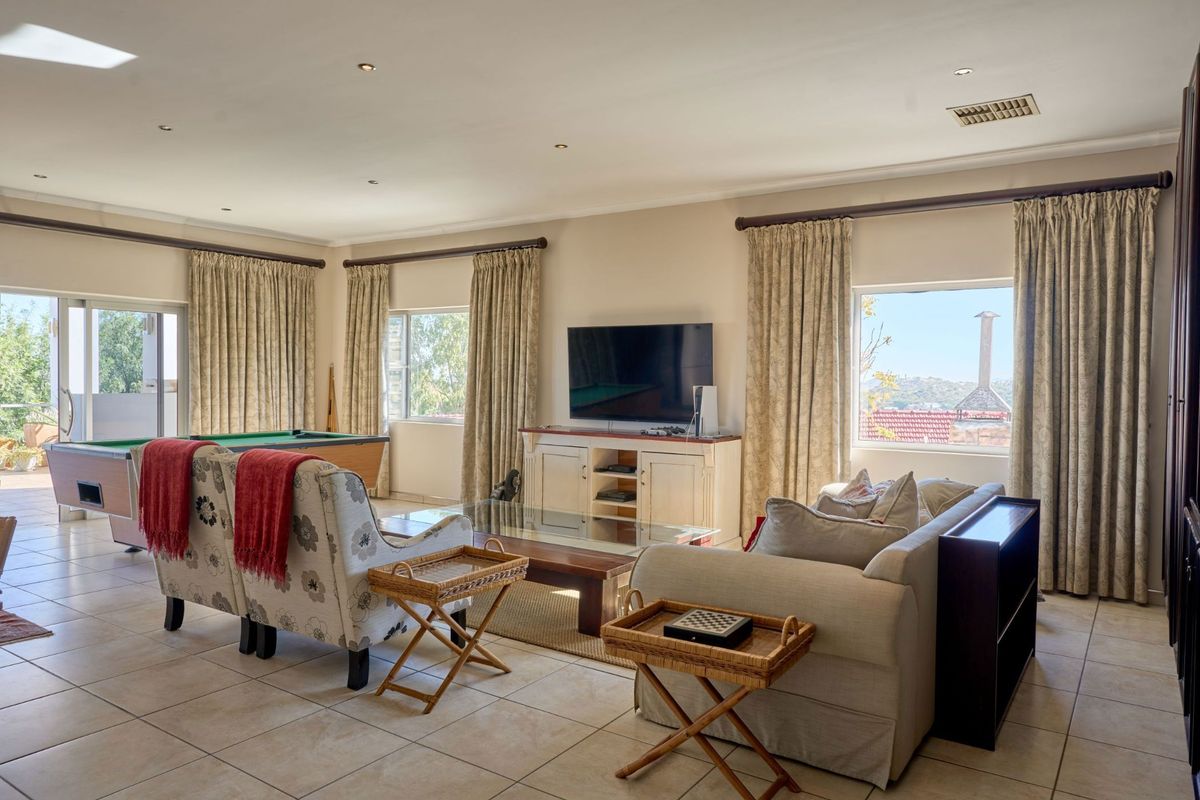 Spacious living room featuring tiled flooring, recessed lighting, and large windows with curtain treatments, offering a comfortable and functional entertainment space.