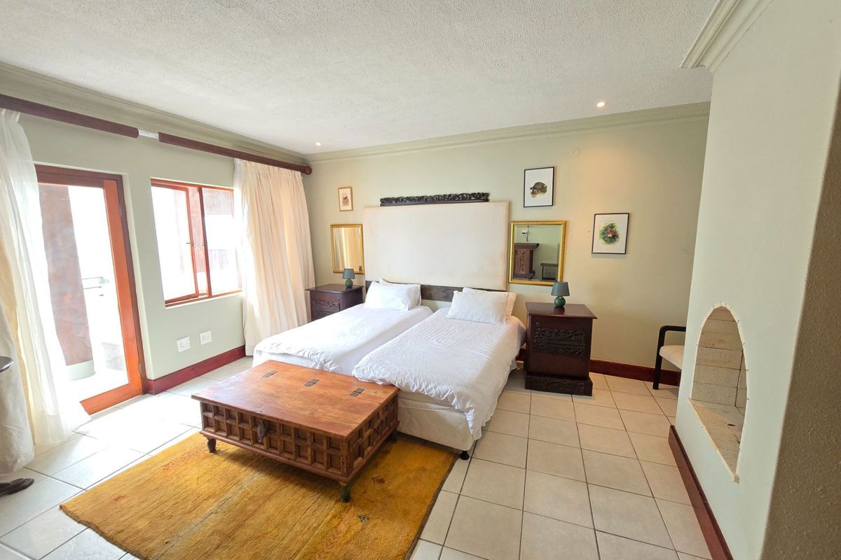 Spacious bedroom featuring tiled flooring, a built-in fireplace, and direct access to an outdoor patio area through glass doors.
