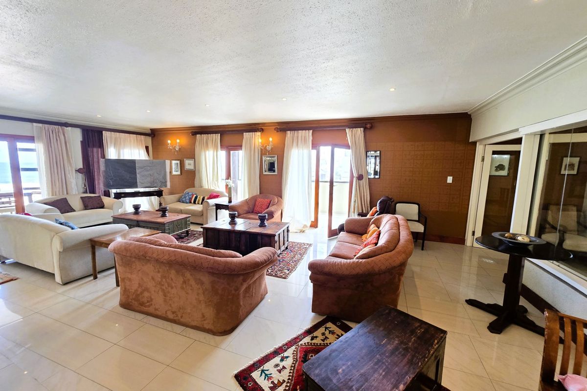 Spacious living area featuring tiled flooring, recessed ceiling lighting, and multiple glass doors providing access to the outdoor balcony.