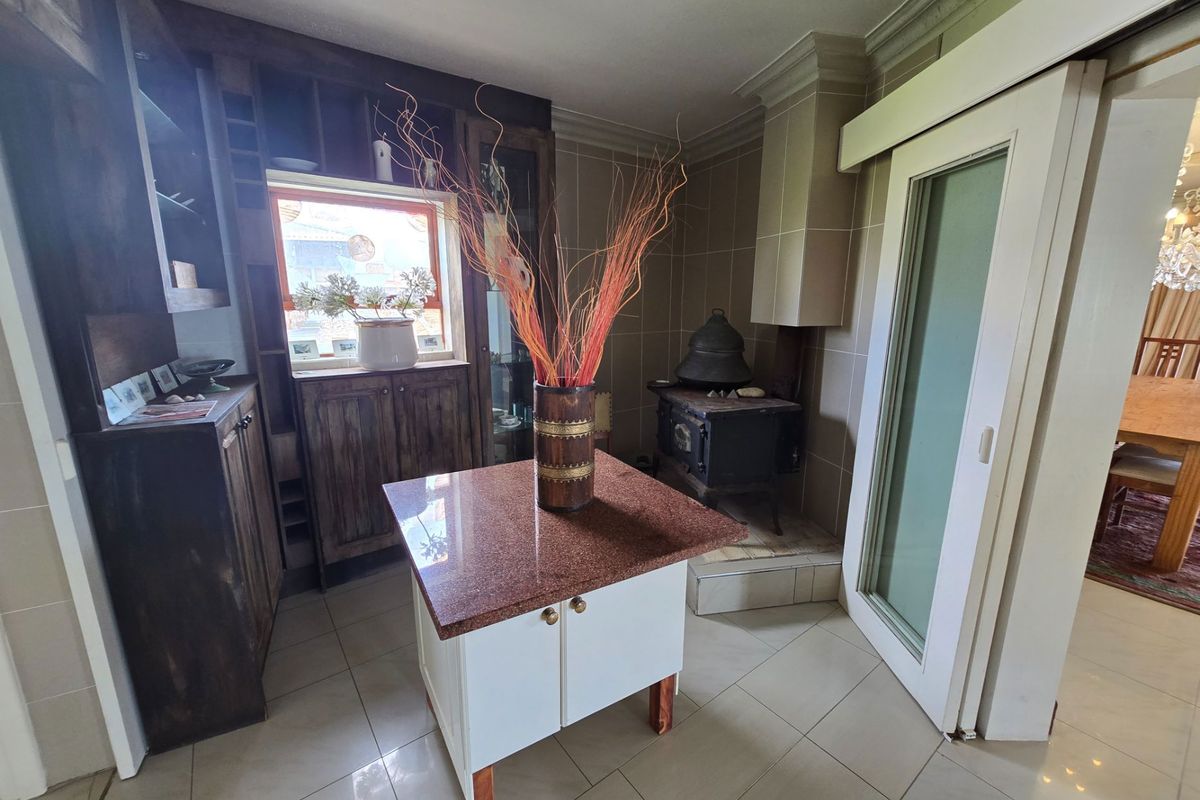 A kitchen area featuring dark wood cabinetry, a granite-topped island, and a built-in wood-burning stove with a tiled hearth.