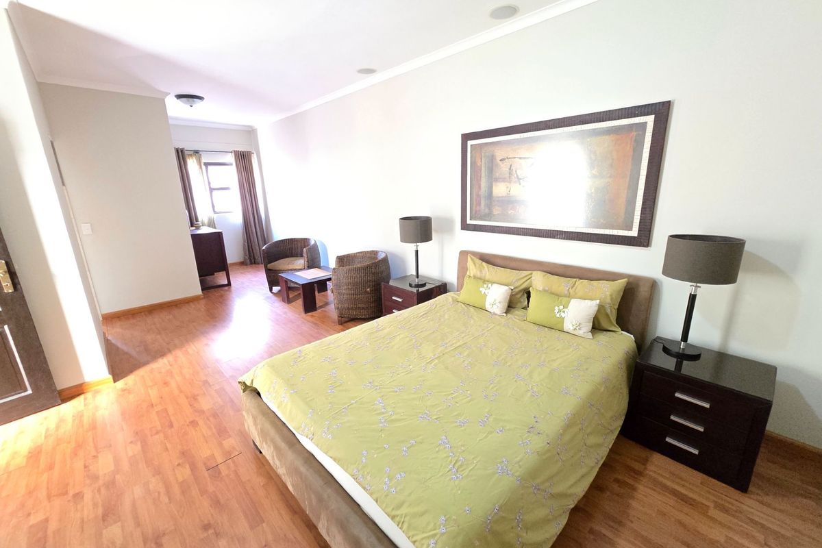 Spacious bedroom featuring laminate flooring, recessed ceiling lighting, and a neutral color palette, offering a comfortable and functional living space.