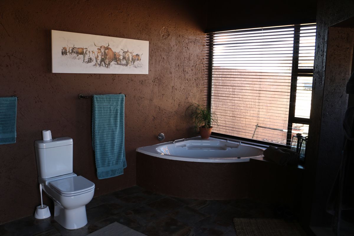 Bathroom featuring a corner bathtub, tiled flooring, and a modern toilet, set against dark textured walls with large window blinds.