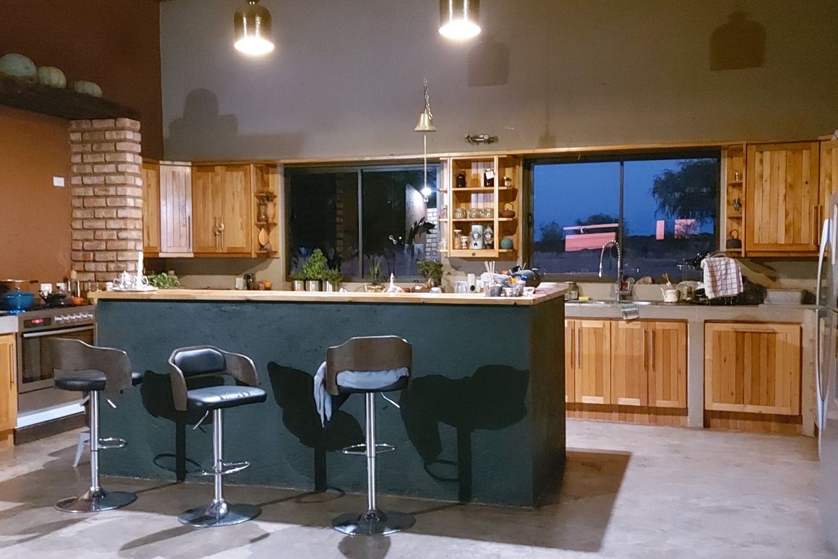 Rustic farmhouse kitchen featuring wooden cabinetry, a central island with breakfast bar seating, concrete countertops, and integrated oven.