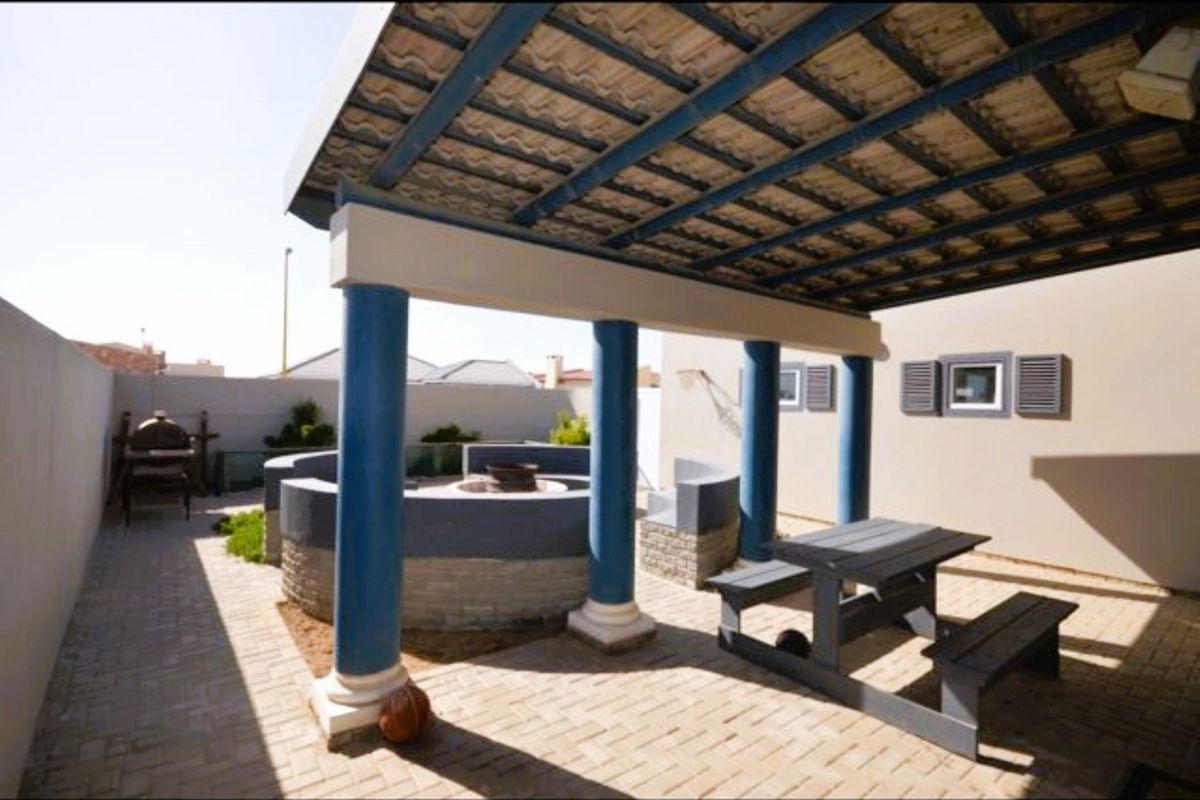 Covered outdoor patio area featuring a built-in circular fire pit, paved flooring, and structural columns, ideal for outdoor entertaining.