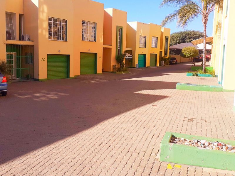 A view of the residential complex driveway featuring multiple units with roller garage doors and paved access areas.