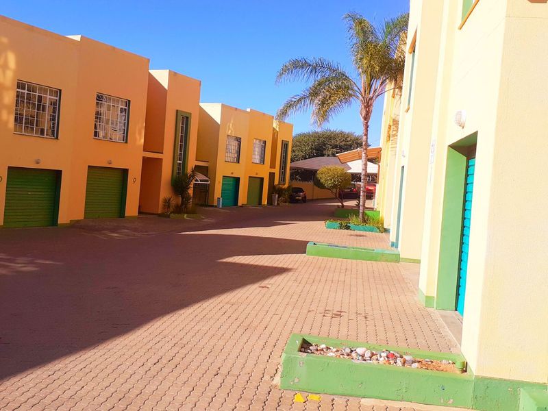 A view of the paved driveway and building facade featuring multiple garage doors and built-in planters in a residential complex.