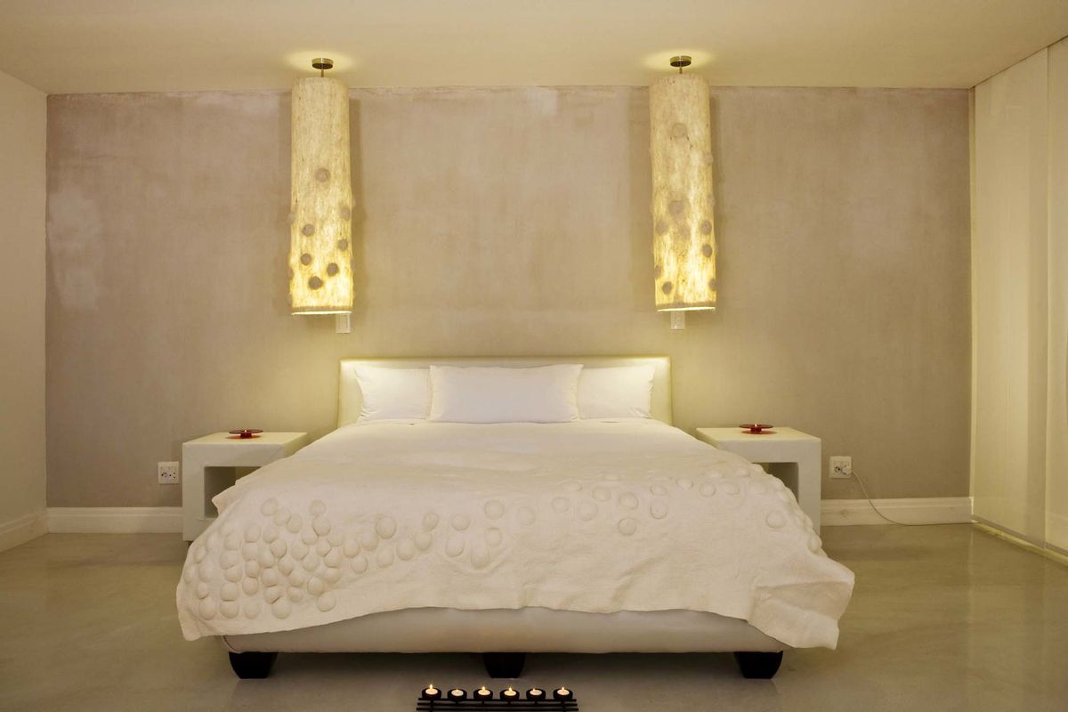 A well-maintained bedroom featuring polished concrete flooring, neutral wall finishes, and integrated wall-mounted lighting fixtures.