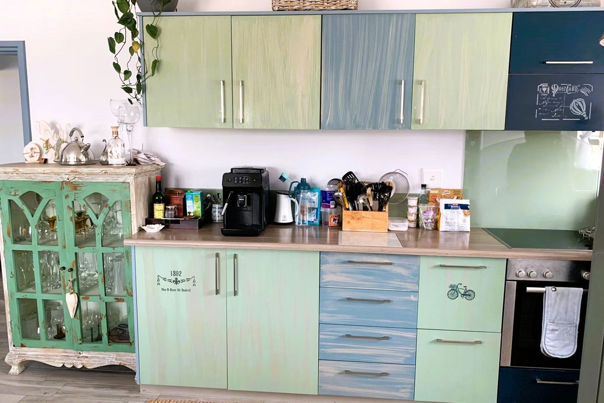 A kitchen area featuring custom-painted cabinetry, a wood-look laminate countertop, and a built-in oven with a glass splashback.