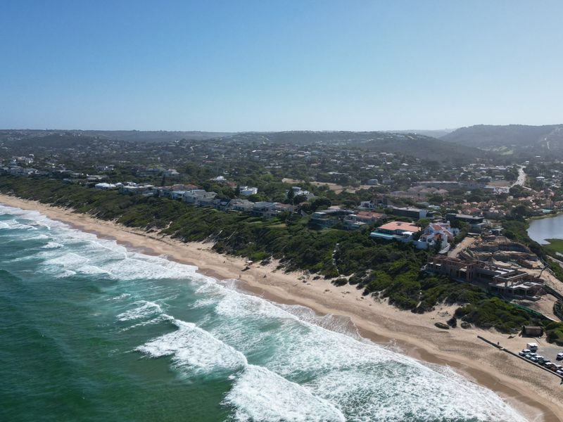 An aerial view of the coastal residential area, showcasing the beach, ocean, and surrounding landscape.