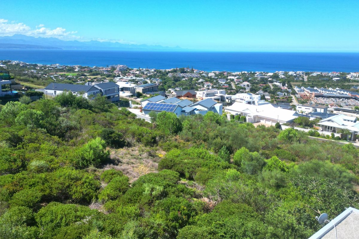 An elevated view overlooking a coastal residential neighborhood with expansive ocean and mountain vistas.