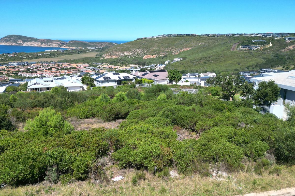 Elevated view overlooking a residential estate with coastal and mountain scenery in the background.