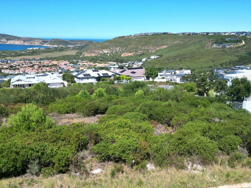 Elevated view overlooking a residential estate with coastal and mountain scenery in the background.