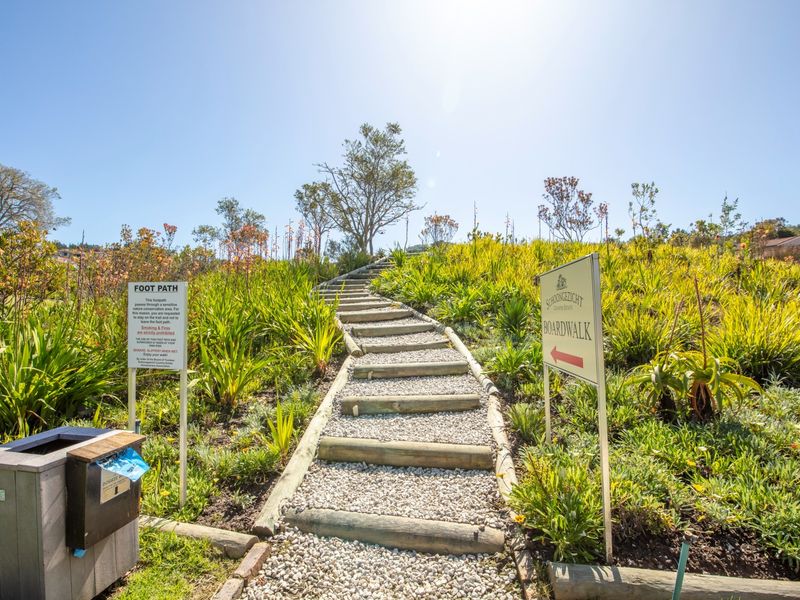 A well-maintained gravel pathway with timber sleeper steps leading through a landscaped garden area within the residential estate.