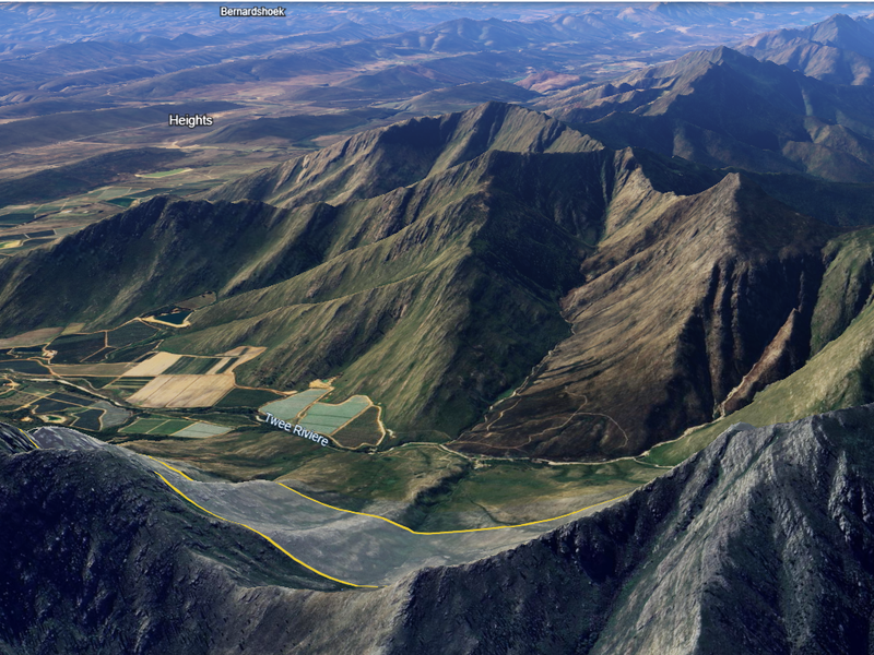 An aerial view of the expansive farm property, showcasing the surrounding mountain ranges, valley landscape, and agricultural fields.