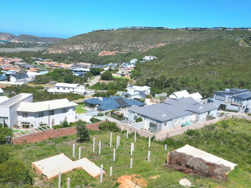 Aerial view of a residential development site featuring concrete foundation slabs and support pillars, set within a suburban landscape.