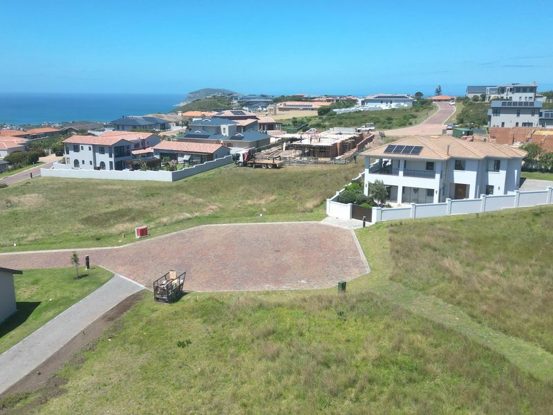 Aerial view of a residential estate featuring vacant land, paved access, and surrounding coastal neighborhood development.