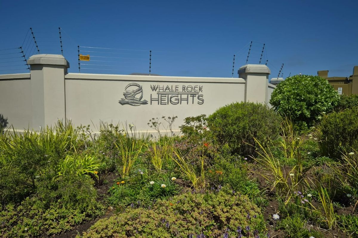 Entrance signage and perimeter wall for Whale Rock Heights residential estate, featuring well-maintained landscaping and security fencing.
