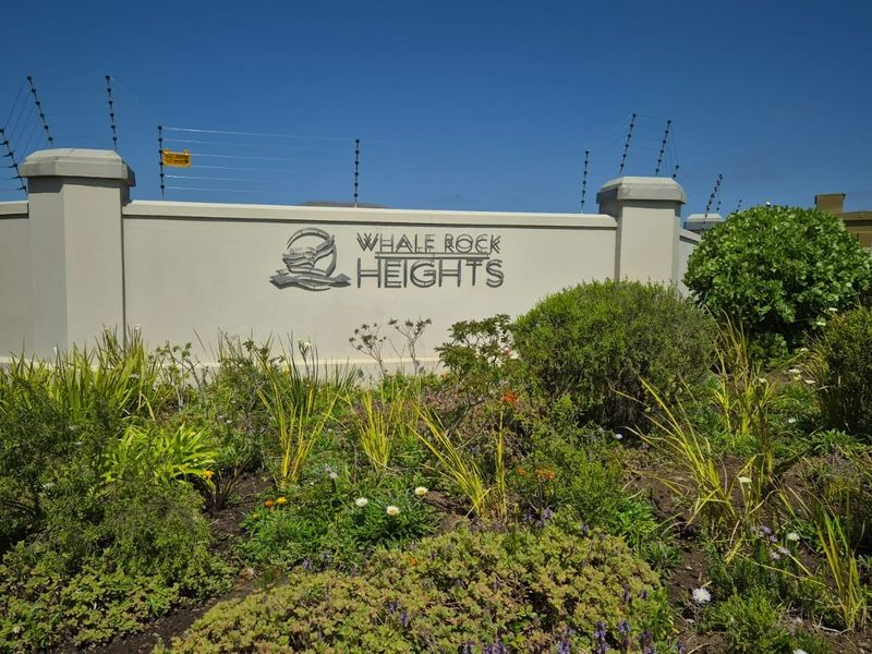 Entrance signage and perimeter wall for Whale Rock Heights residential estate, featuring well-maintained landscaping and security fencing.