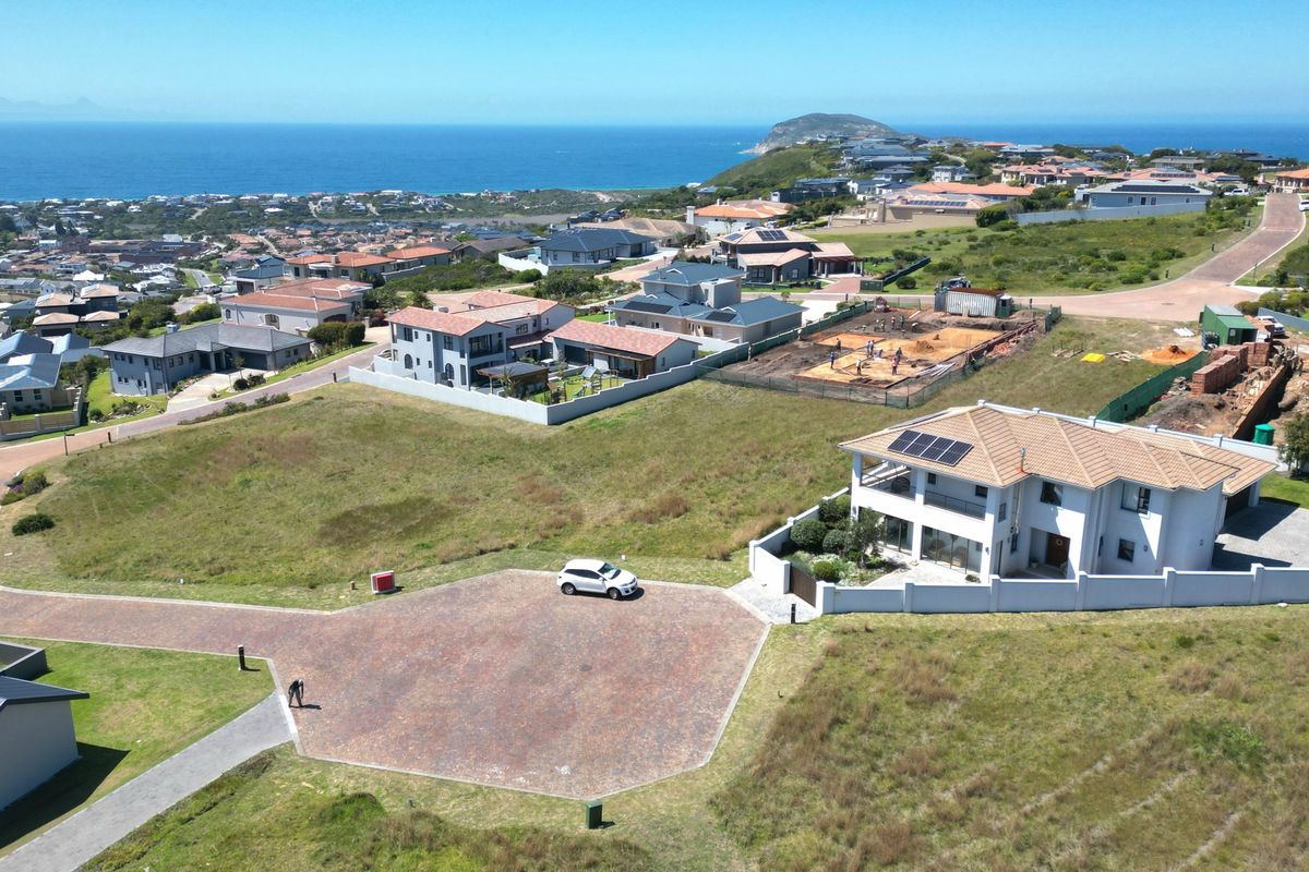 Aerial view of a vacant residential plot in a coastal estate, featuring established surrounding homes and paved access.