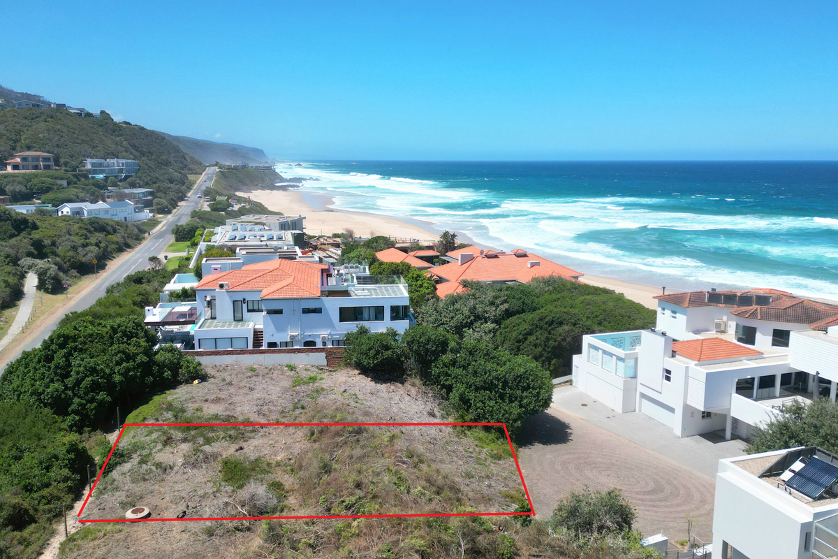 Aerial view of a vacant residential plot situated in a prime coastal location with direct proximity to the beach and surrounding residential properties.