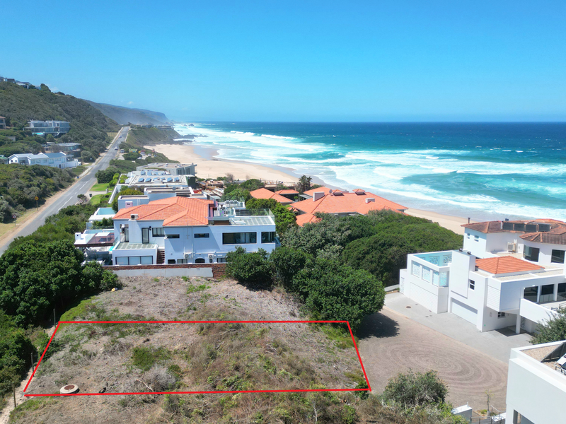 Aerial view of a vacant residential plot situated in a prime coastal location with direct proximity to the beach and surrounding residential properties.