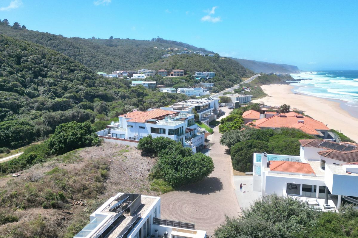 An aerial view of a coastal residential estate situated along the beach, featuring established homes and natural vegetation.