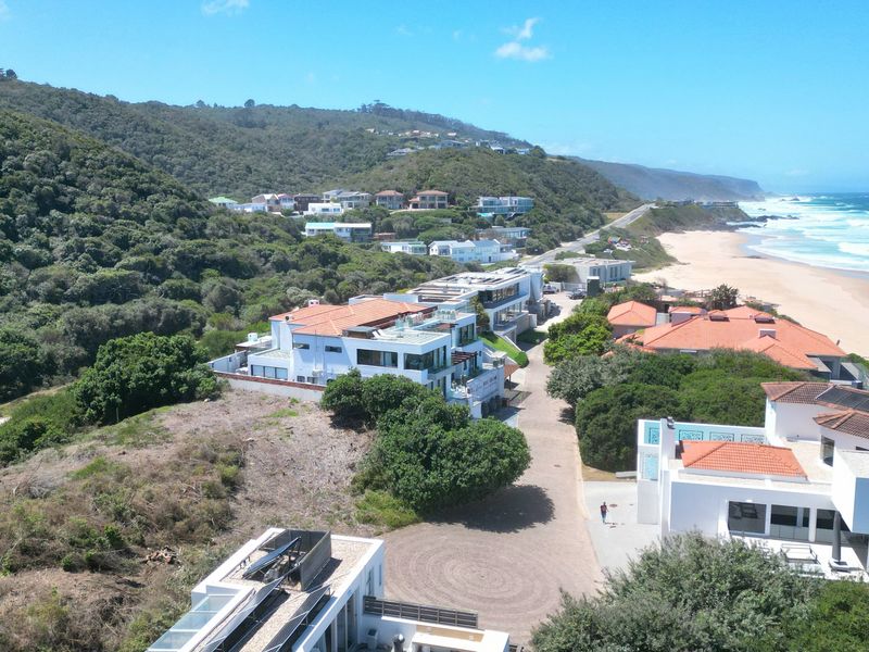 An aerial view of a coastal residential estate situated along the beach, featuring established homes and natural vegetation.