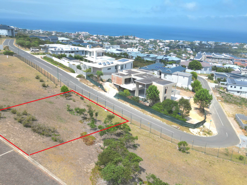 Aerial view of a vacant residential plot in a developed coastal estate, featuring clear boundary lines and proximity to existing infrastructure.