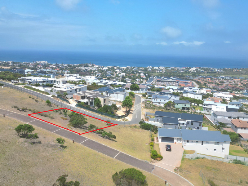 An aerial view of a vacant residential plot in a coastal estate, highlighting the land boundaries and surrounding neighborhood infrastructure.