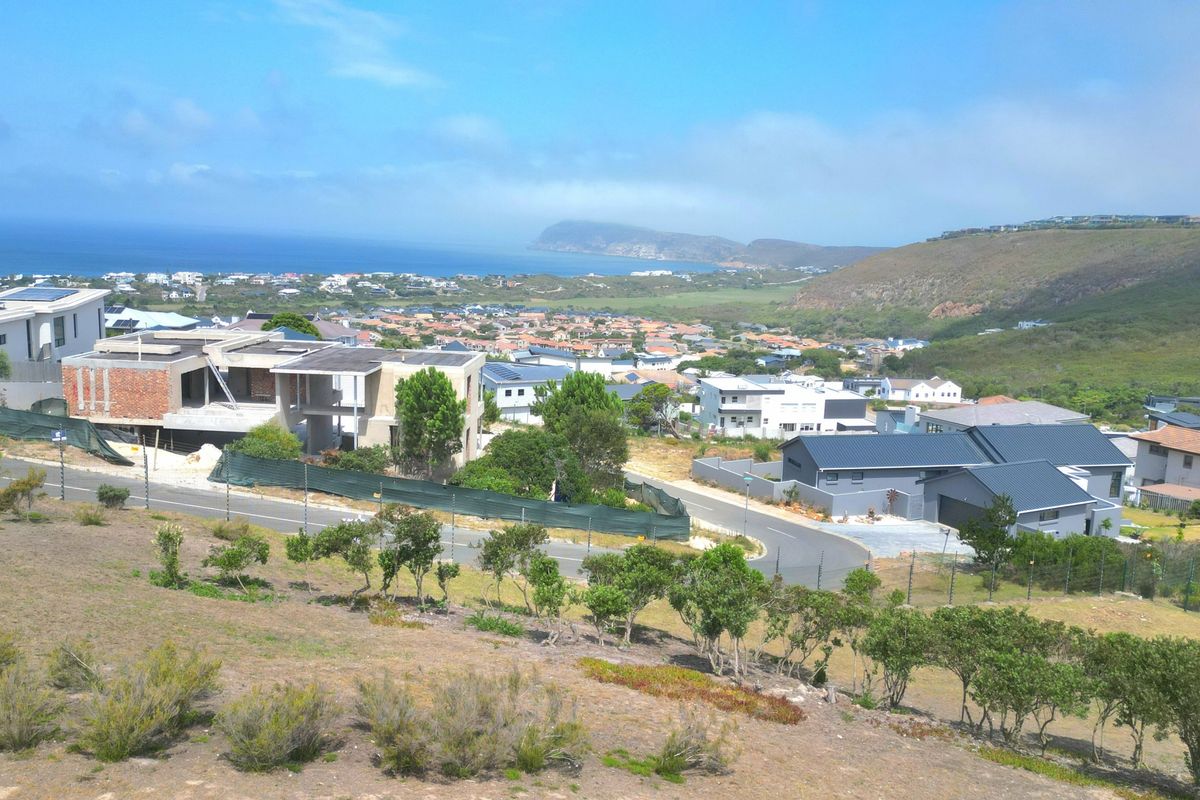 Elevated panoramic view overlooking a coastal residential estate, surrounding hills, and the ocean in the distance.