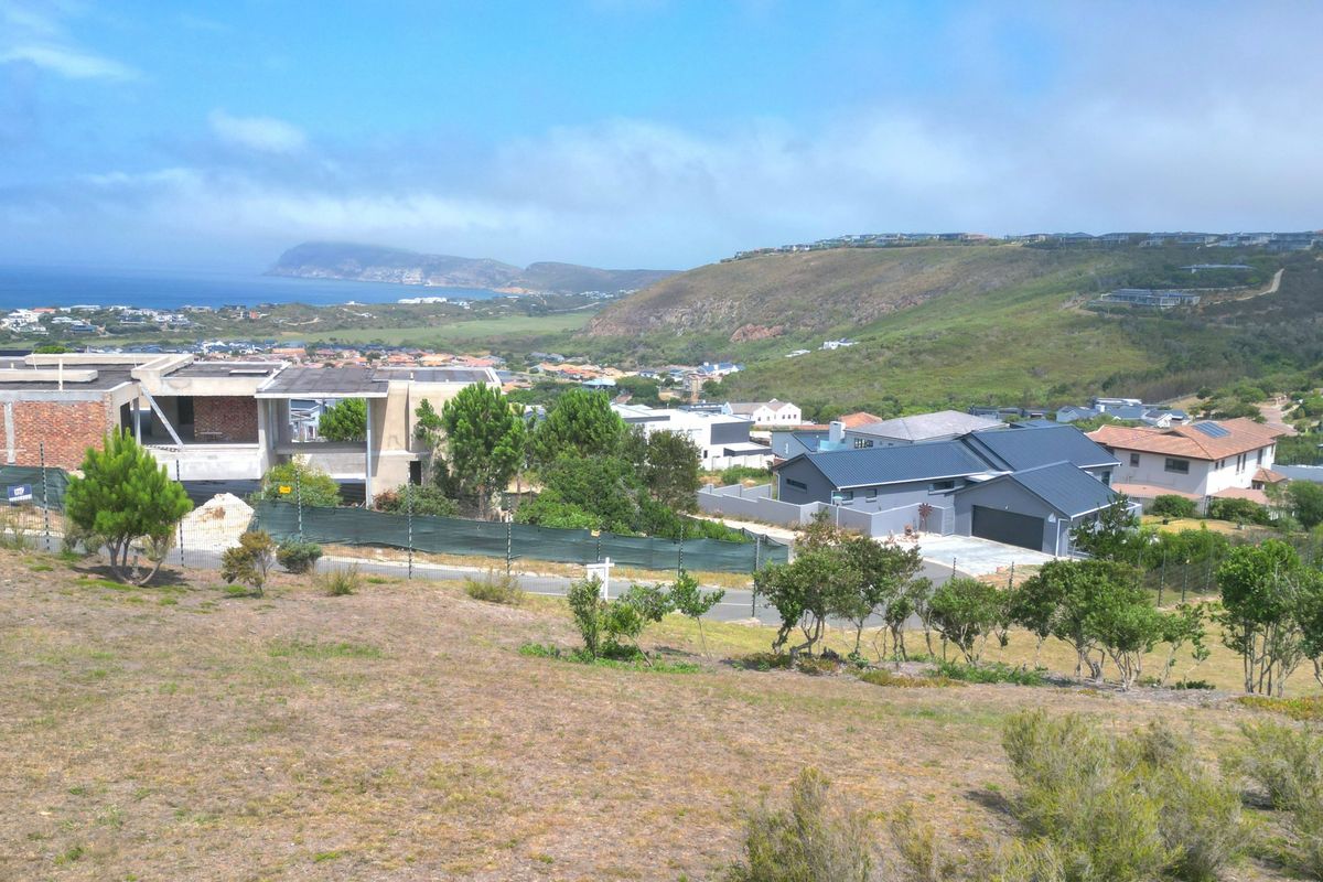 Elevated view overlooking a residential estate with coastal and mountain scenery in the background.