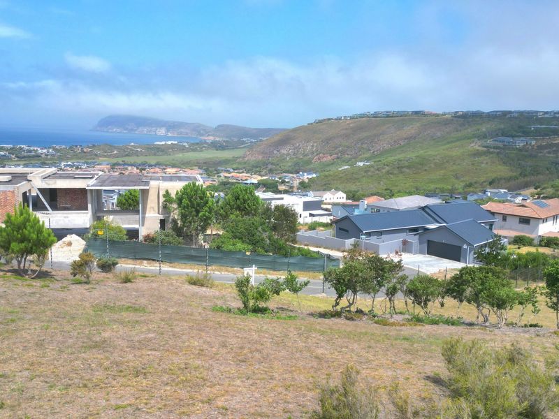 Elevated view overlooking a residential estate with coastal and mountain scenery in the background.