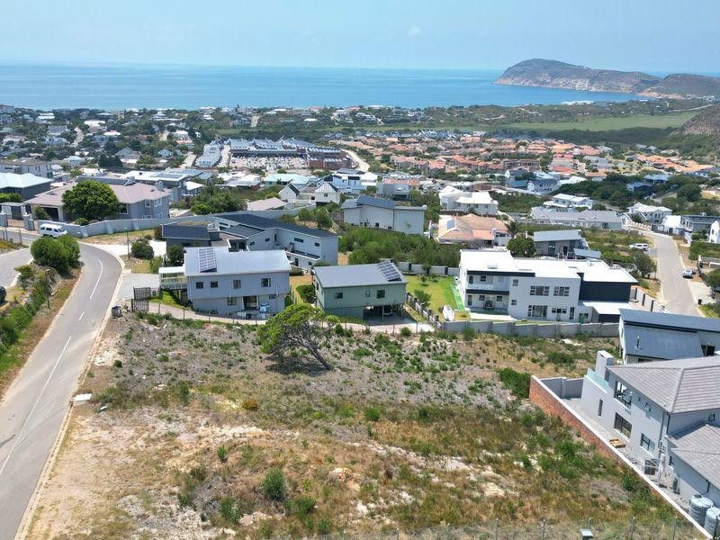 Aerial view of a vacant residential plot situated within an established coastal neighborhood, offering potential for development with scenic ocean views.