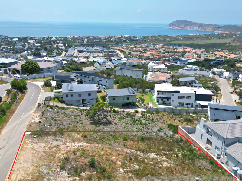 Aerial view of a vacant residential plot situated in a developed coastal neighborhood with surrounding homes and ocean views.