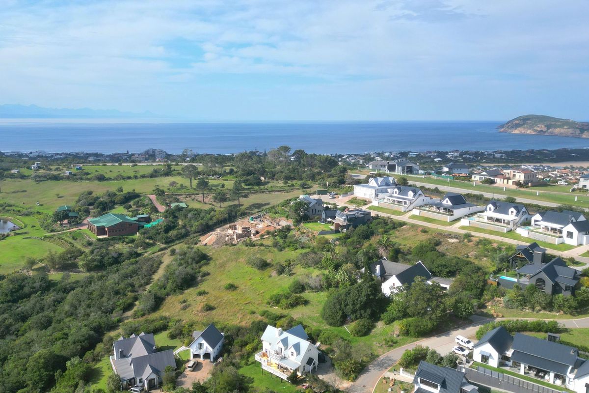 An aerial view of a residential estate featuring coastal landscape, established homes, and surrounding natural vegetation with ocean views.