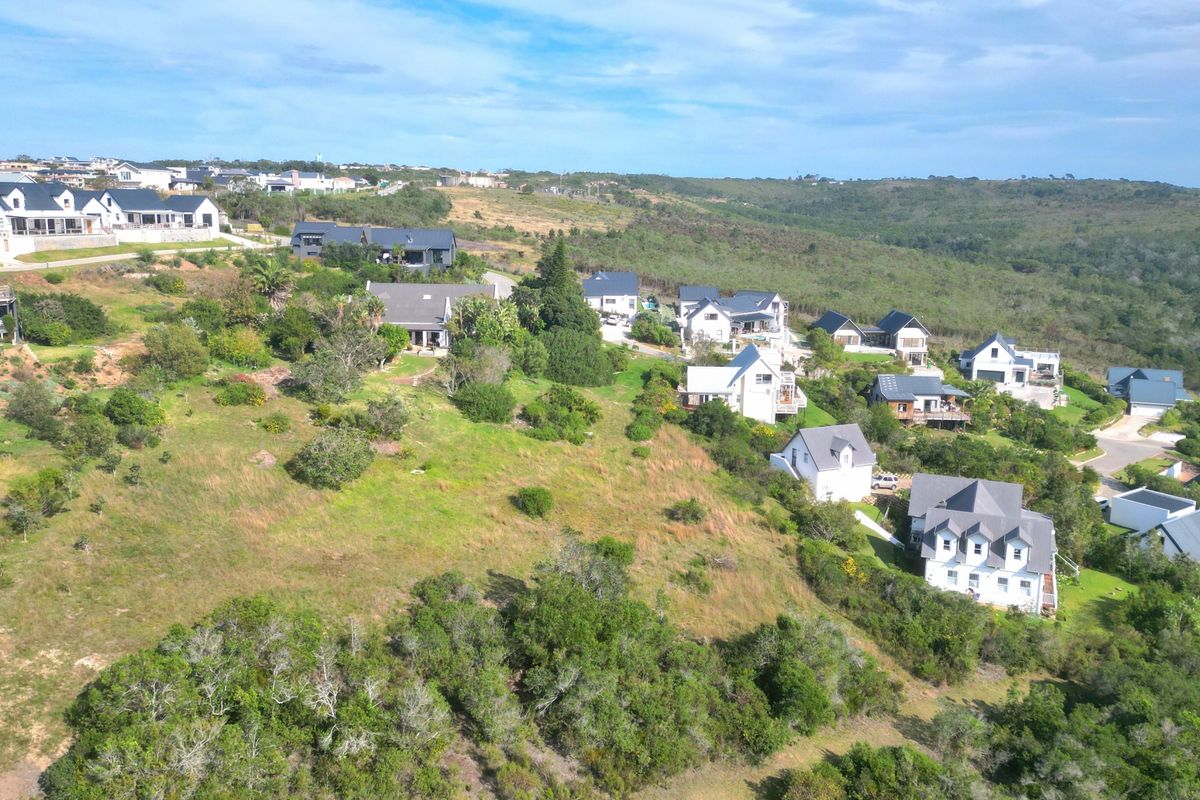 An aerial view of a residential estate featuring multiple homes situated on a sloped landscape with surrounding natural vegetation.